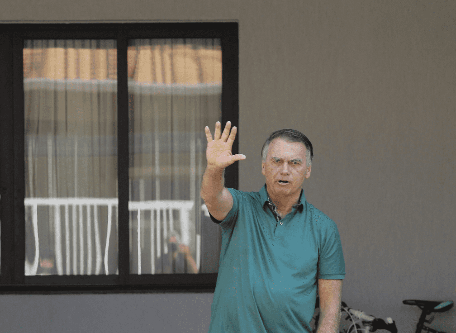 Em prisão domiciliar, Bolsonaro acena para jornalistas na porta de casa